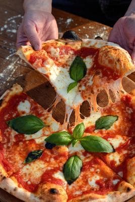 Fresh pizza being pulled apart